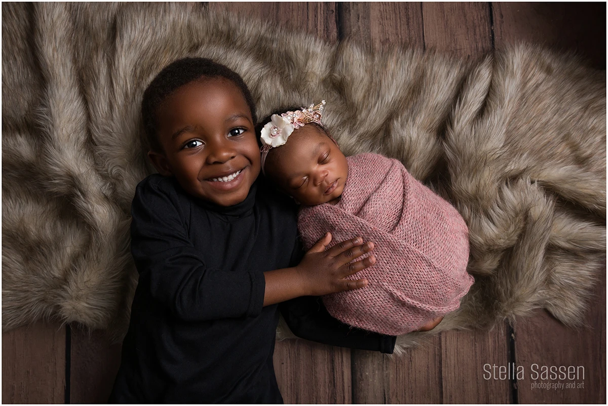 A newborn baby and her big brother posing for a photo shoot