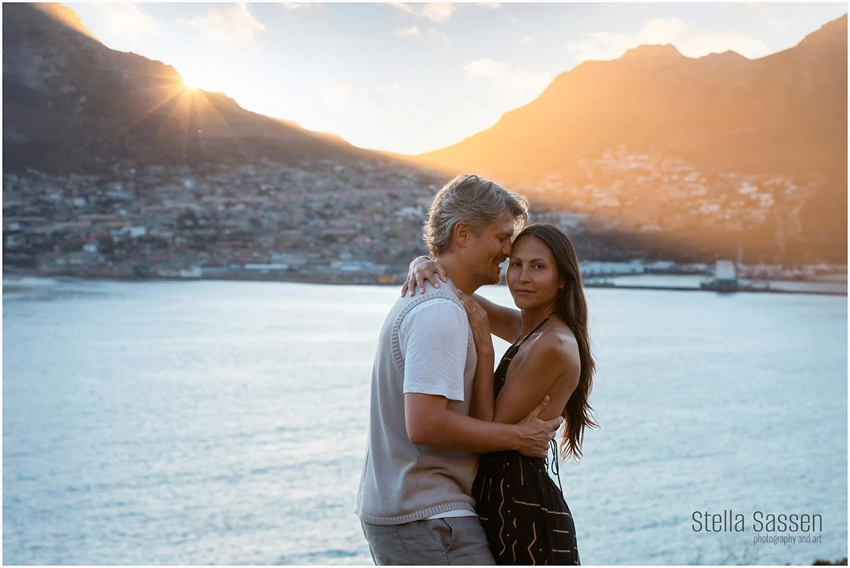 Destination engagement photoshoot in Cape Town at sunset with a couple embracing and city and ocean views behind them.