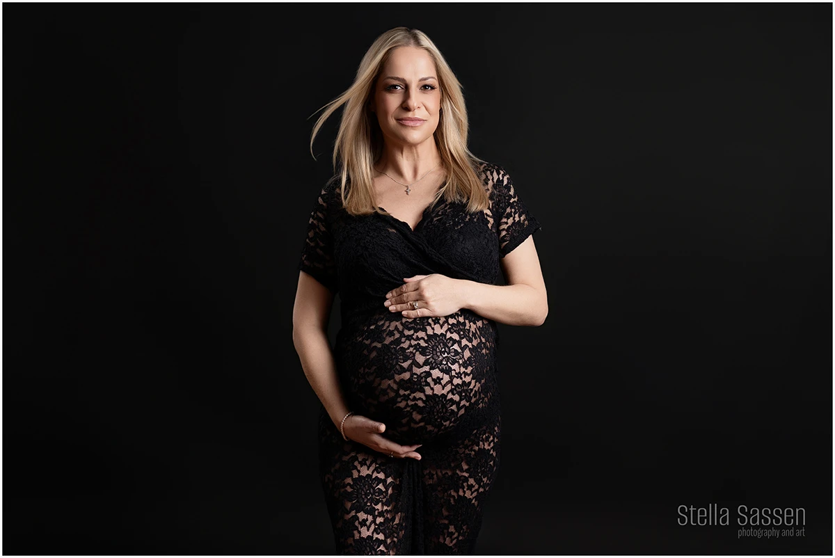 portrait of pregnant woman with her hair blowing and posing in a lace dress
